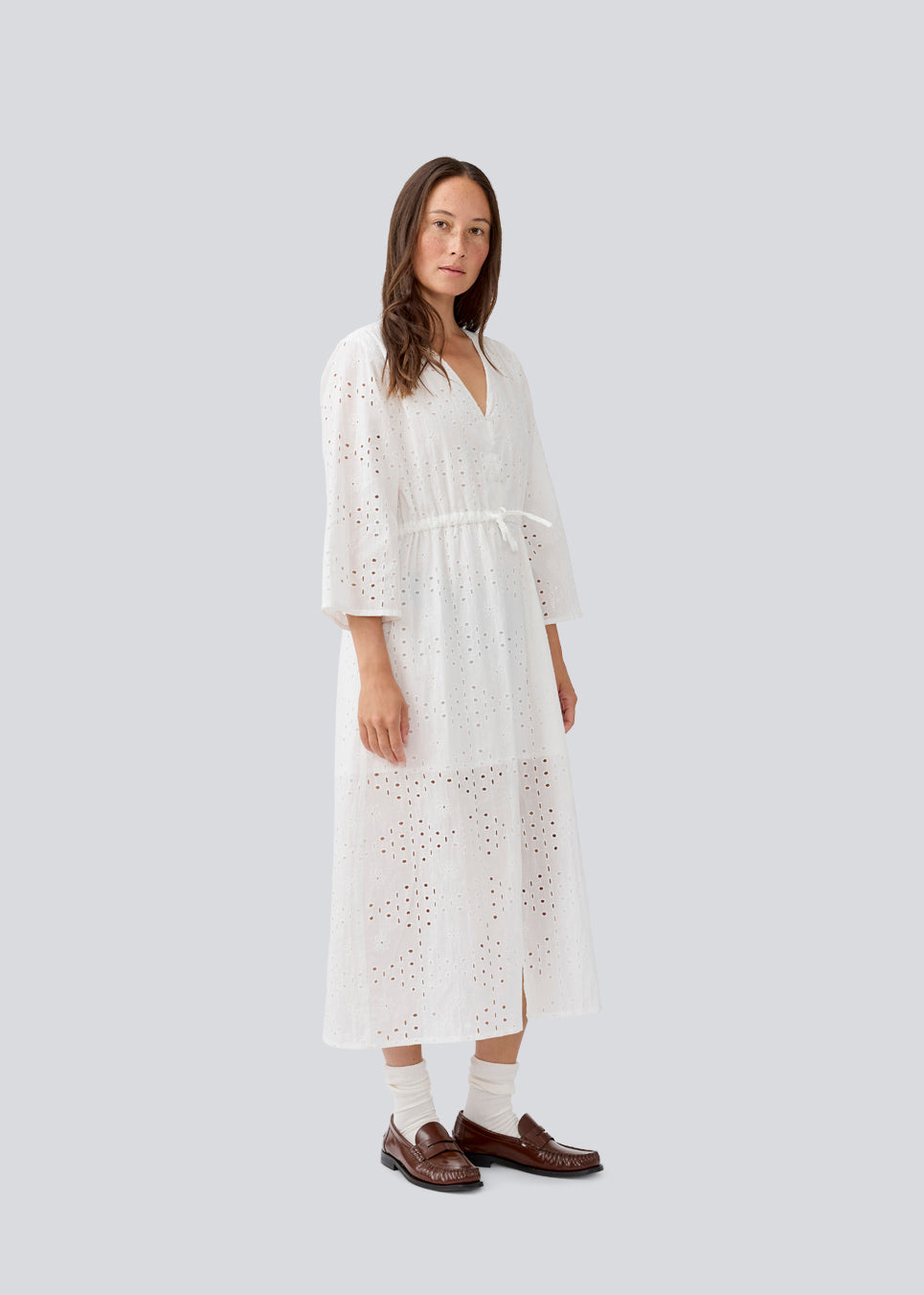 Maxi dress in broderie anglaise. MisoMD dress has a loose fit, v-neck and a tieband at the waist. 