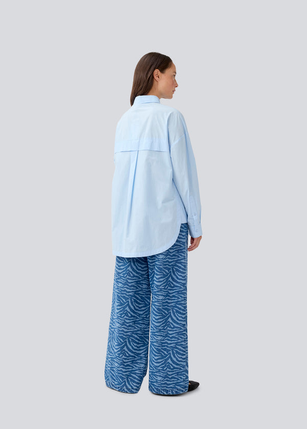 Blue classic shirt with an oversize fit. MyraMD shirt has a hidden buttonclosure in front and slits in the sides. The model is 177 cm and wears a size S/36.