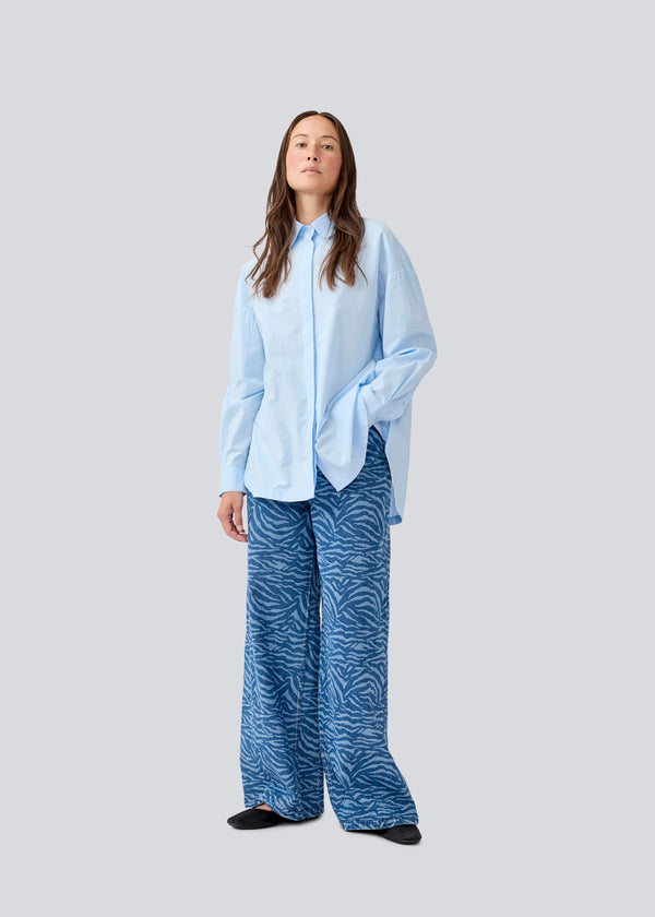 Blue classic shirt with an oversize fit. MyraMD shirt has a hidden buttonclosure in front and slits in the sides. The model is 177 cm and wears a size S/36.