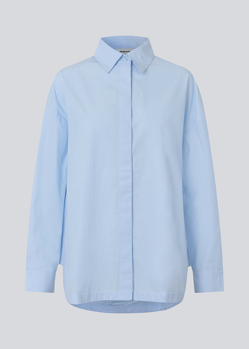Blue classic shirt with an oversize fit. MyraMD shirt has a hidden buttonclosure in front and slits in the sides. The model is 177 cm and wears a size S/36.