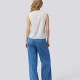 Sleeveless white top in broderie anglaise. NanetteMD top has a high neck and a button closure in front.