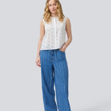 Sleeveless white top in broderie anglaise. NanetteMD top has a high neck and a button closure in front.