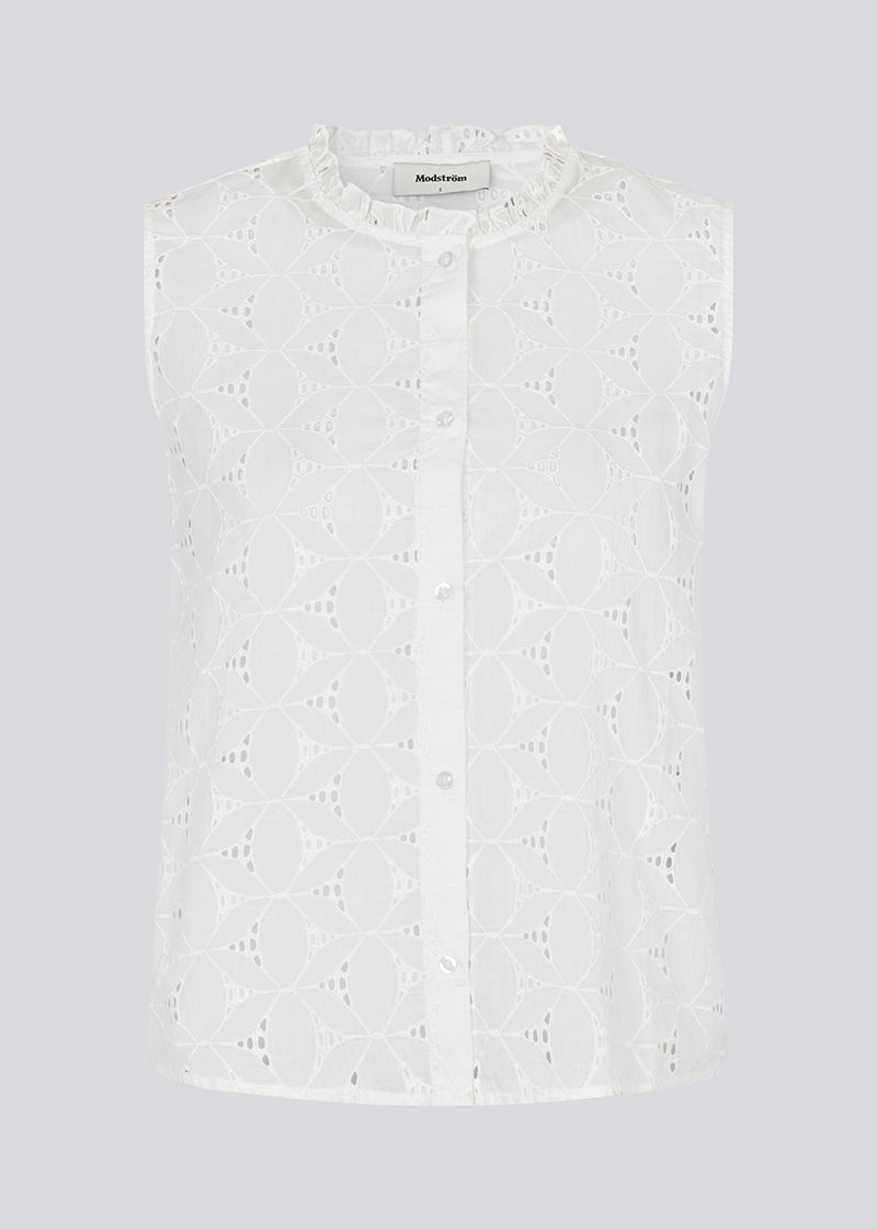 Sleeveless white top in broderie anglaise. NanetteMD top has a high neck and a button closure in front.

