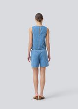 Sleeveless blue top with a round neck in cotton denim. NaomaMD solid top has a loose fit and an opening in the neck with a button closure.