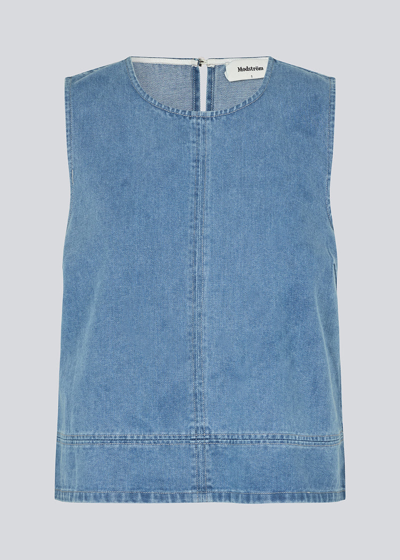 Sleeveless blue top with a round neck in cotton denim. NaomaMD solid top has a loose fit and an opening in the neck with a button closure.