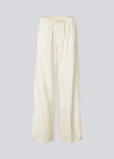 Loose white pants with wide legs made in 100% cotton. NasirMD pants have side pockets, an elastic waist with a string, and a stitched press fold at the front.