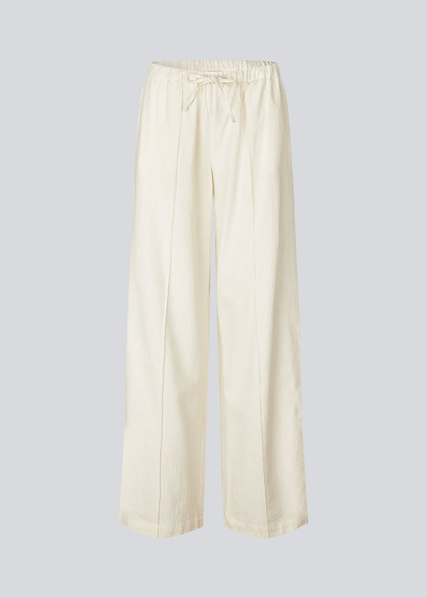 Loose white pants with wide legs made in 100% cotton. NasirMD pants have side pockets, an elastic waist with a string, and a stitched press fold at the front.