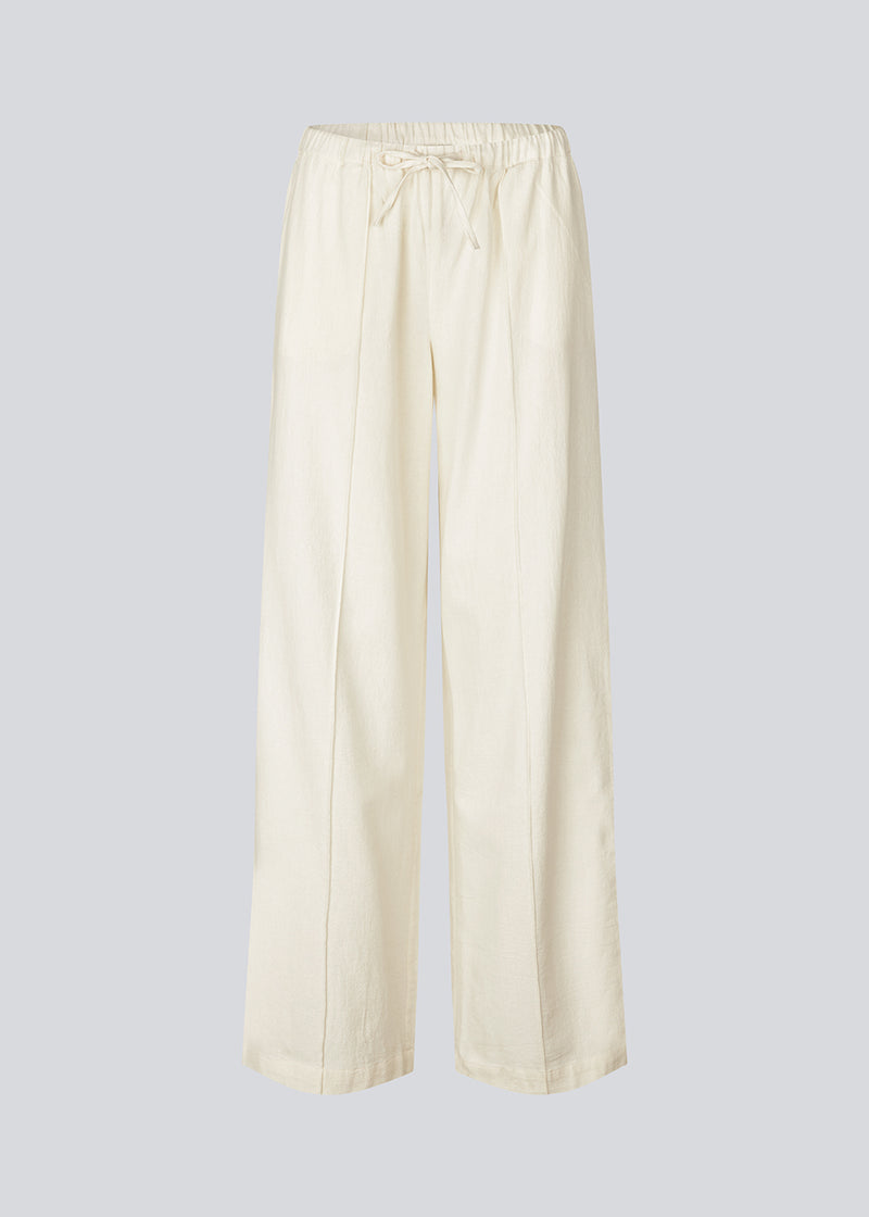 Loose white pants with wide legs made in 100% cotton. NasirMD pants have side pockets, an elastic waist with a string, and a stitched press fold at the front.