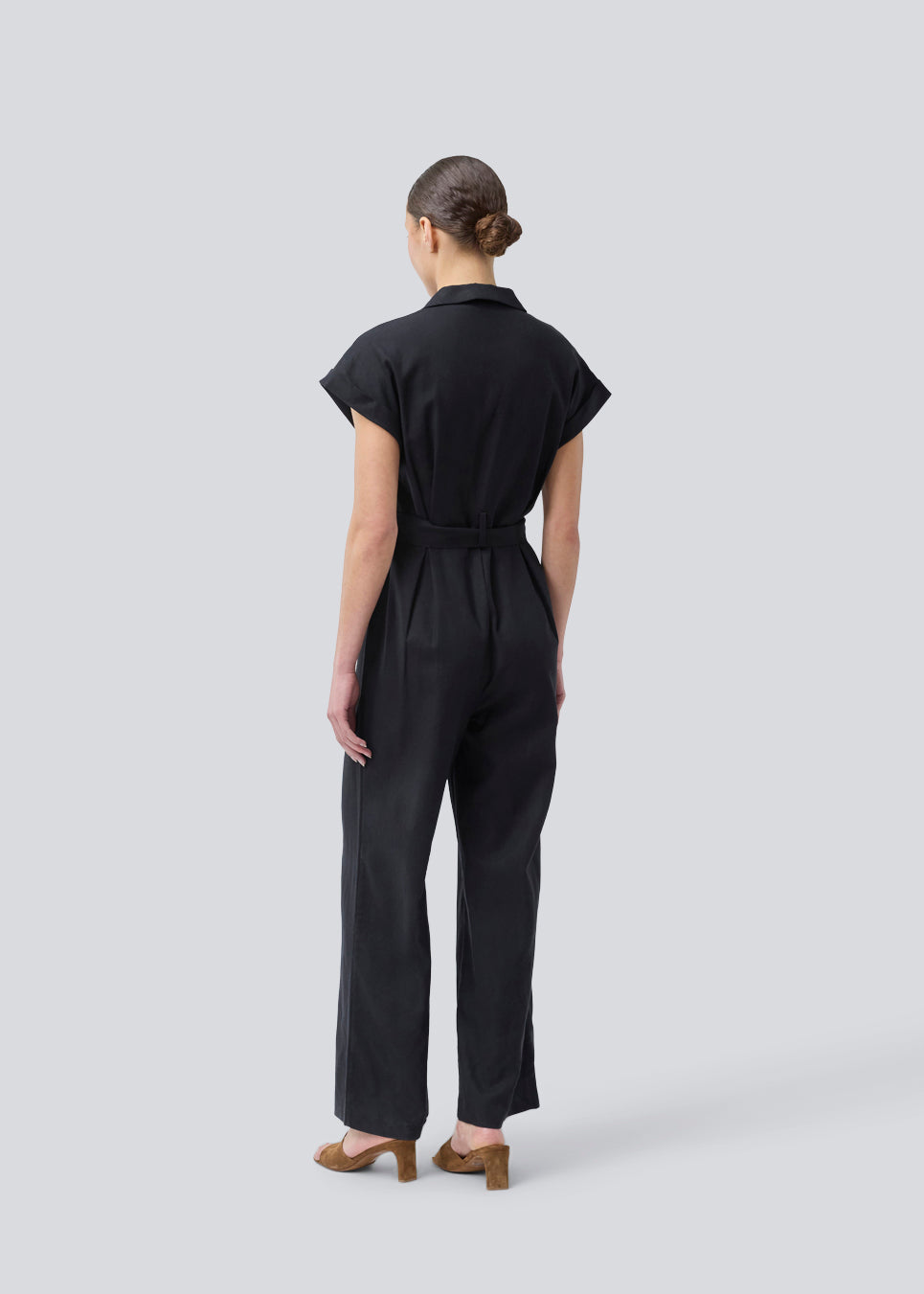 Black jumpsuit with wide legs and a tieband at the waist. NedraMD jumpsuit has a collar, v-neck, and a zipper at front.