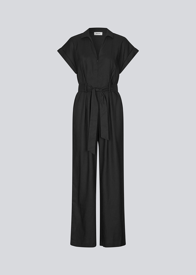 Black jumpsuit with wide legs and a tieband at the waist. NedraMD jumpsuit has a collar, v-neck, and a zipper at front.