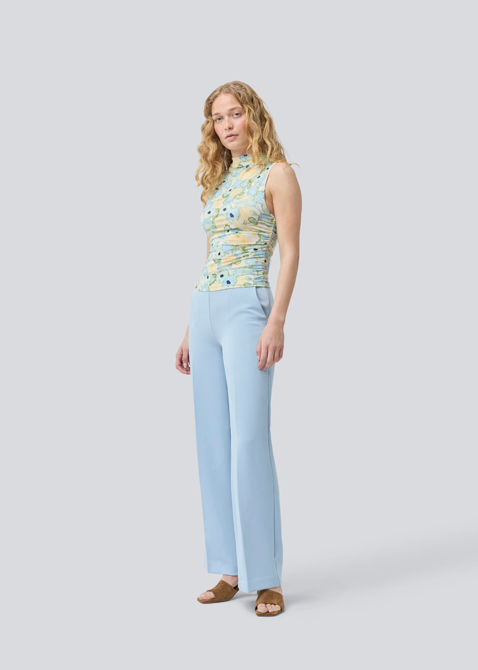 Classic pants in light blue with pressfolds and straight legs. Nelli pants are closed by an hidden zipper at the side with an elastic waistband for a more comfortable fit. The model is 175 cm and wears a size S/36
