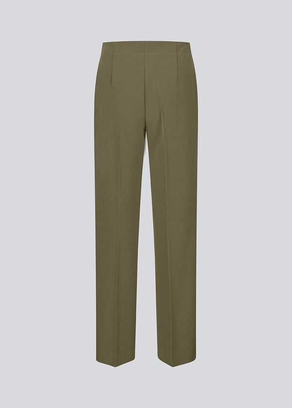 Classic dark green pants with pressfolds and straight legs. Nelli pants are closes by an hidden zipper at the side with an elastic waistband for a more comfortable fit.