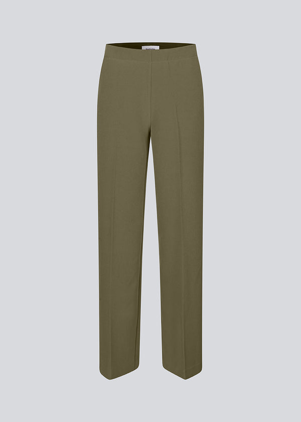 Classic dark green pants with pressfolds and straight legs. Nelli pants are closes by an hidden zipper at the side with an elastic waistband for a more comfortable fit.