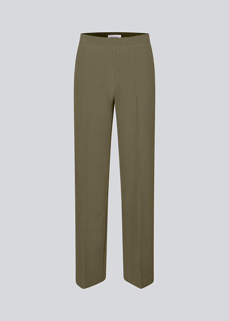 Classic dark green pants with pressfolds and straight legs. Nelli pants are closes by an hidden zipper at the side with an elastic waistband for a more comfortable fit.