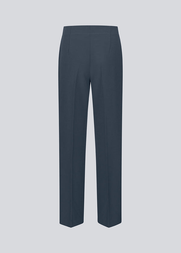 Classic navy pants in navy blue with pressfolds and straight legs. Nelli pants are closed by a hidden zipper at the side with an elastic waistband for a more comfortable fit.