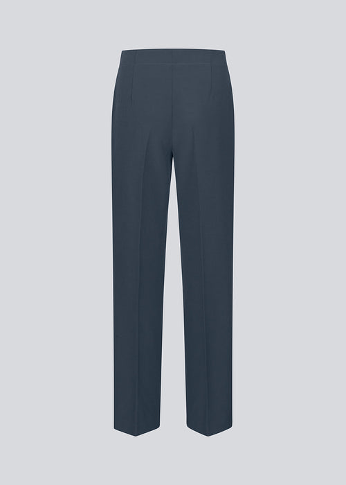 Classic navy pants in navy blue with pressfolds and straight legs. Nelli pants are closed by a hidden zipper at the side with an elastic waistband for a more comfortable fit.