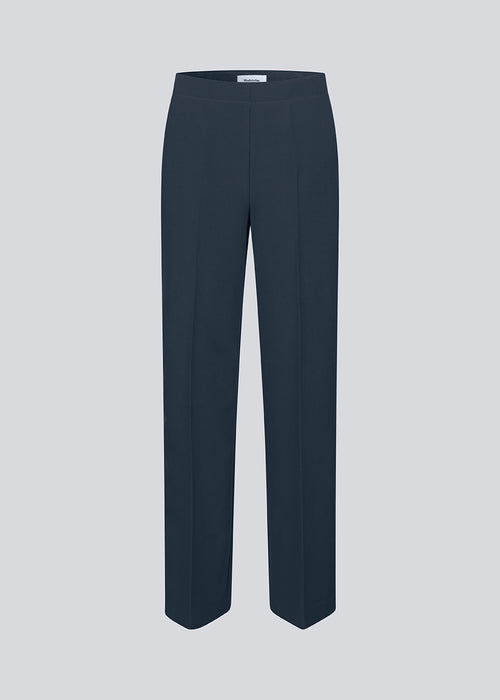 Classic navy pants in navy blue with pressfolds and straight legs. Nelli pants are closed by a hidden zipper at the side with an elastic waistband for a more comfortable fit.