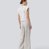Sleeveless white top with frill details and a button closure in front. NIkkoMD top is slightly cropped and has a v-neck.
