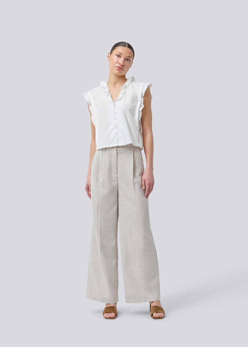 Sleeveless white top with frill details and a button closure in front. NIkkoMD top is slightly cropped and has a v-neck.
