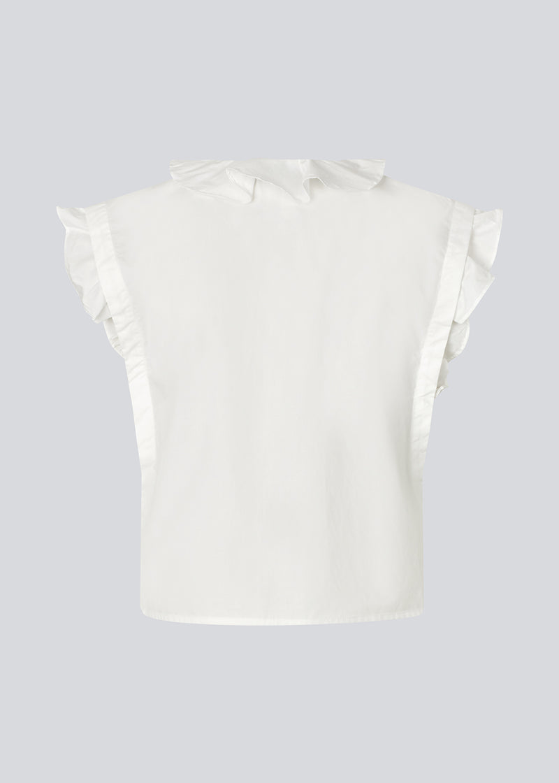 Sleeveless white top with frill details and a button closure in front. NIkkoMD top is slightly cropped and has a v-neck.