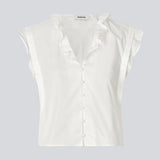 Sleeveless white top with frill details and a button closure in front. NIkkoMD top is slightly cropped and has a v-neck.
