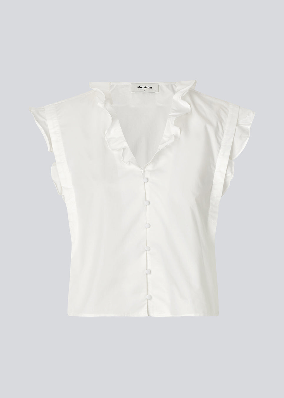 Sleeveless white top with frill details and a button closure in front. NIkkoMD top is slightly cropped and has a v-neck.