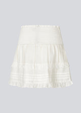 Short white skirt in 100% organic cotton. NillaMD short skirt has a loose skirt with pleats and frill details, and an elastic waist with a smock.
