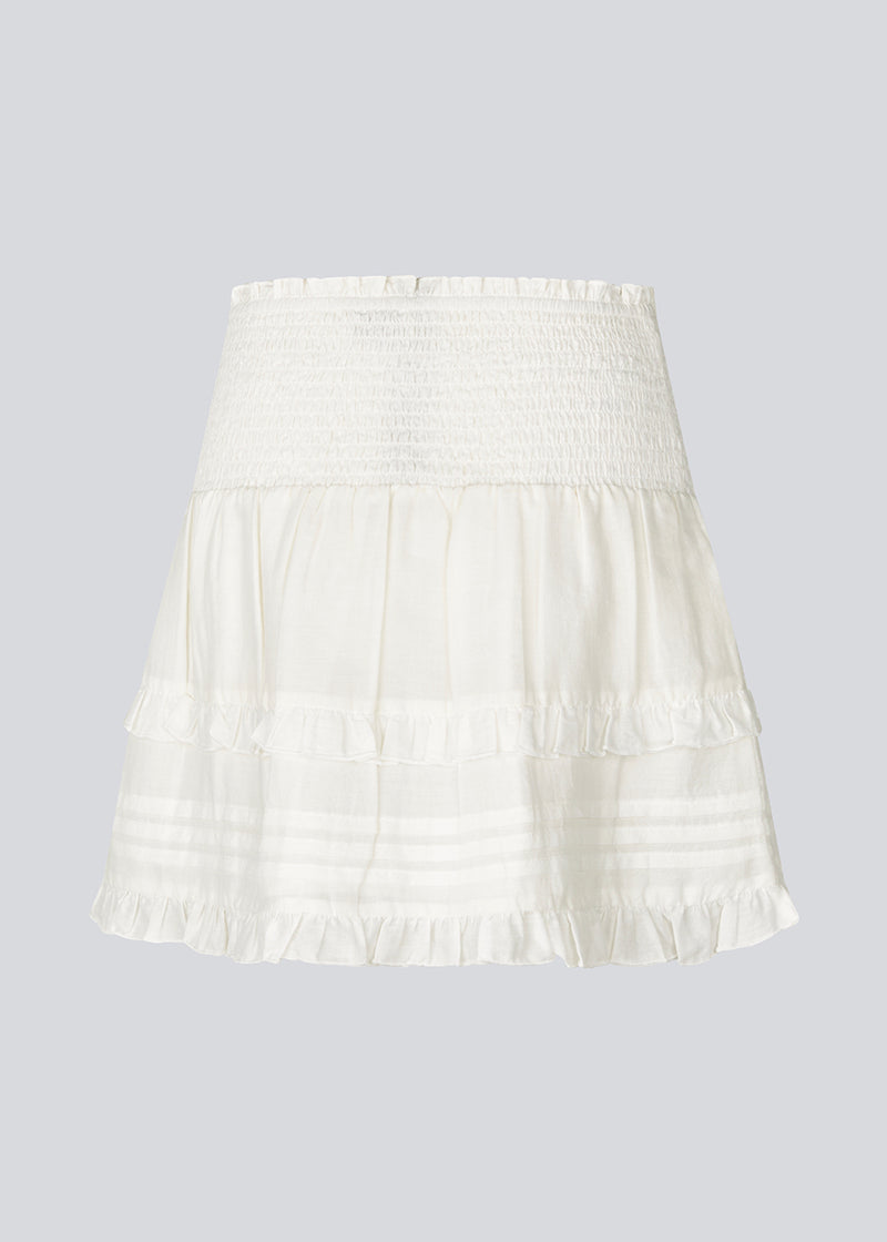 Short white skirt in 100% organic cotton. NillaMD short skirt has a loose skirt with pleats and frill details, and an elastic waist with a smock.
