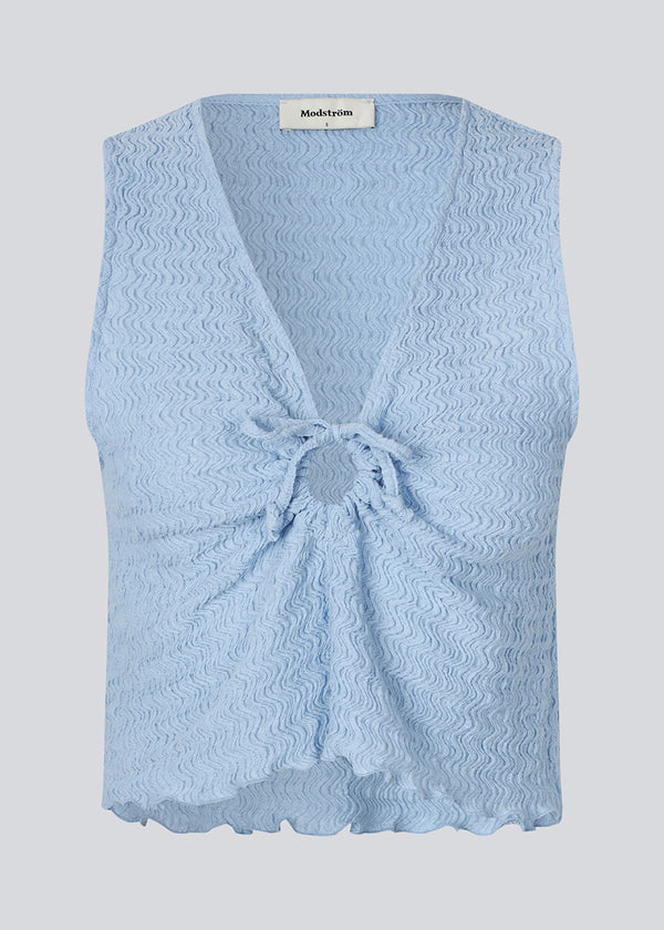 Sleeveless blue top with an opening with a tiedetail in front. NolineMD top is slightly cropped and has a loose fit and v-neck.