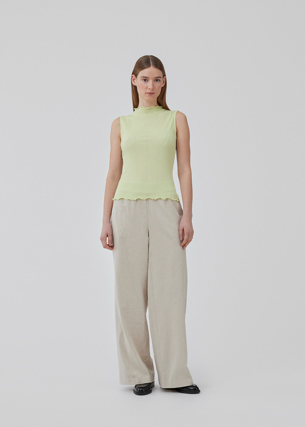 Sleeveless top in light green-yellow in a structured material with a high neck. OasisMD top has lettuce hems at the neckline, armhole, and hem. The model is 175 cm and wears a size S/36.<br>