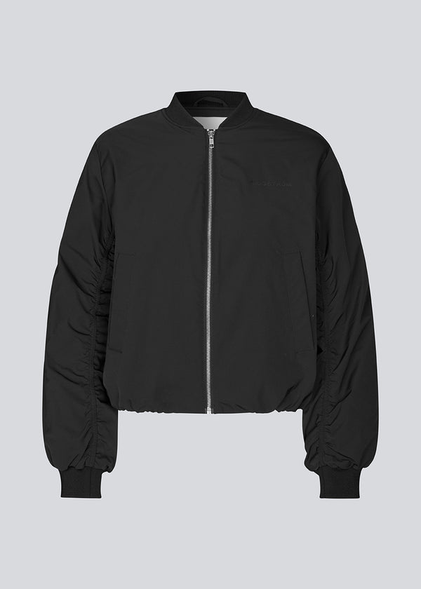 Padded black bomber jacket with gatherings at the sleeves. Obimd jacket is slightly cropped and has a zipper closure and two front pockets.&nbsp;