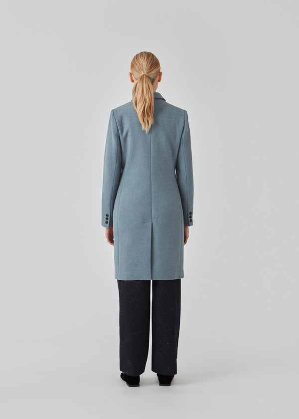 Beautiful, knee-length wool coat. Odelia coat, in the color Blue Moon, is closed at front by 4 buttons and is fitted around the waist, which gives a feminine look. Because of the high content of wool the jacket will be perfect for fall and the mild winters.