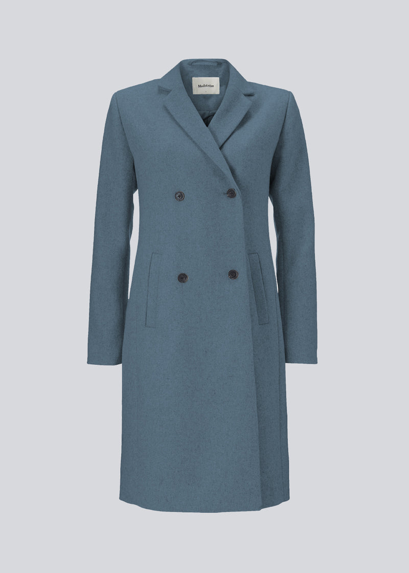 Beautiful, knee-length wool coat in blue. Odelia coat, in the color Blue Moon, is closed at front by 4 buttons and is fitted around the waist, which gives a feminine look. Because of the high content of wool the jacket will be perfect for fall and the mild winters.