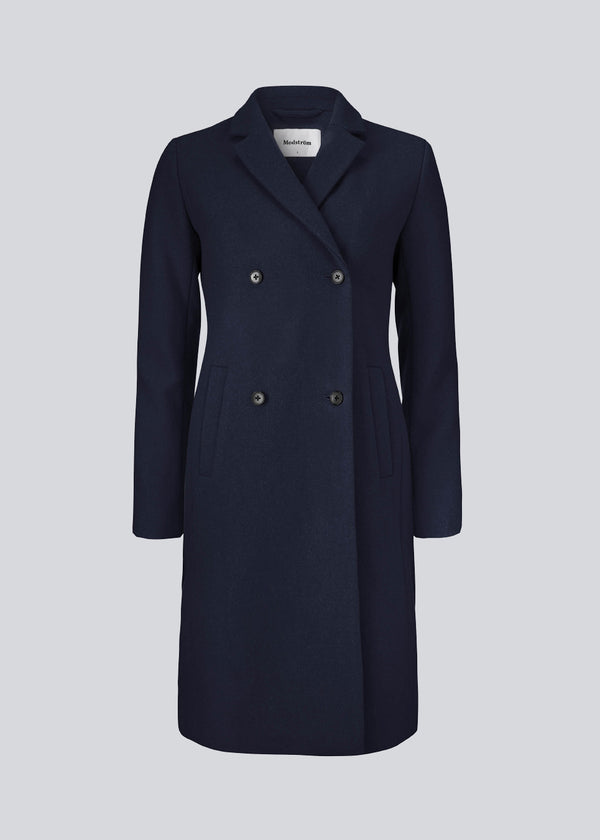 Beautiful, knee-length wool coat in navy sky. Odelia coat is closed at front by 4 buttons and is fitted around the waist, which gives a feminine look. Because of the high content of wool the jacket will be perfect for fall and the mild winters.
