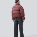 Red puffer jacket with a high neck in 100% recycled polyester. Odinmd jacket has a zipper closure and an adjustable strap at the sleeve. The model is 175 cm and wears a size s/36.