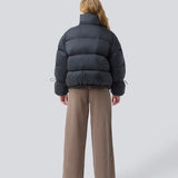 Black puffer jacket with a high neck in 100% recycled polyester. Odinmd jacket has a zipper closure and an adjustable strap at the sleeve. The model is 175 cm and wears a size s/36.