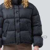 Black puffer jacket with a high neck in 100% recycled polyester. Odinmd jacket has a zipper closure and an adjustable strap at the sleeve. The model is 175 cm and wears a size s/36.
