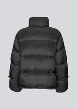Black puffer jacket with a high neck in 100% recycled polyester. Odinmd jacket has a zipper closure and an adjustable strap at the sleeve. The model is 175 cm and wears a size s/36.