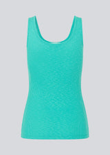 Olla top in turquoise is a simple tanktop in a soft ribmaterial. The top has a tight and figure-hugging silhouette which has a soft feel under a knitted sweater or shirt. The model is 173 cm and wears a size S/36
