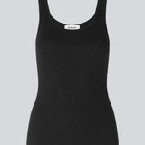 Olla top is a simple black tank top in a soft rib-material. The top has a tight and figure-hugging silhouette which has a soft feel under a knitted sweater or shirt.