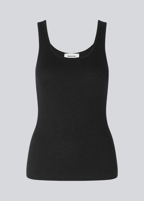 Olla top is a simple black tank top in a soft rib-material. The top has a tight and figure-hugging silhouette which has a soft feel under a knitted sweater or shirt.