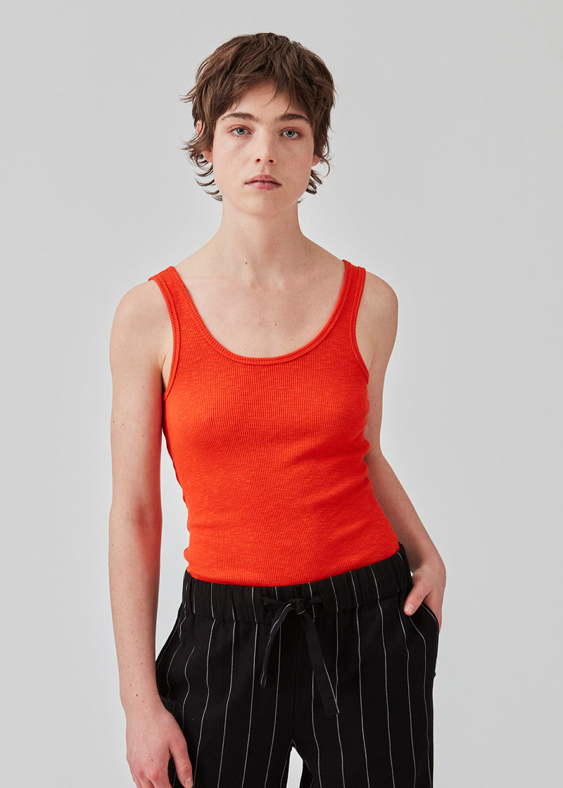 Olla top in bright cherry is a simple tanktop in a soft rib material. The top has a tight and figure-hugging silhouette which has a soft feel under a knitted sweater or shirt. The model is 173 cm and wears a size S/36
