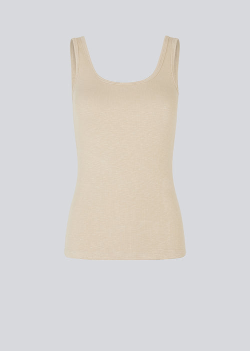 Olla top is a simple beige tank top in a soft rib-material. The top has a tight and figure-hugging silhouette which has a soft feel under a knitted sweater or shirt.