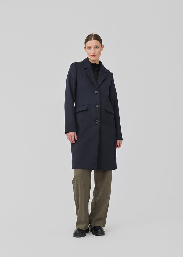 Beautiful, long wool coat in navy. Pamela coat is closed by 3 big buttons at front and is waisted, which gives a feminine look. Because of the high content of wool you will be able to keep warm all through fall and the mild winters.