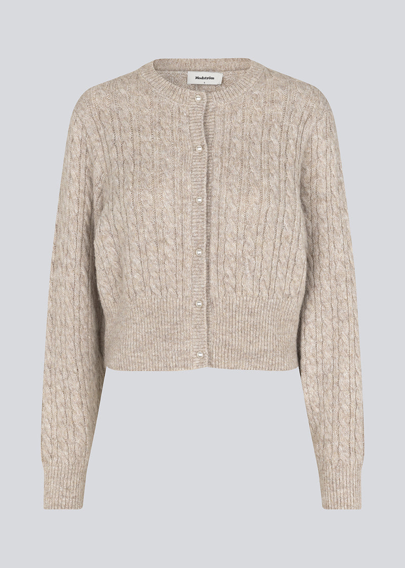 Knitted cable knit cardigan with pearl buttons. Pammiemd cardigan has a round neckline and ribbed hem.