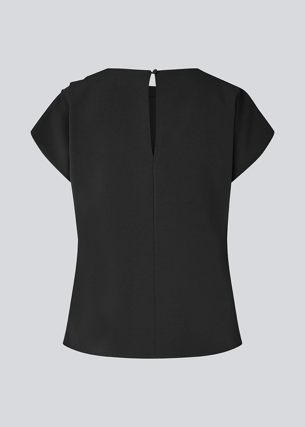 Fitted top with ruffled details. Pandymd top has short sleeves and an opening in the back with button closure.