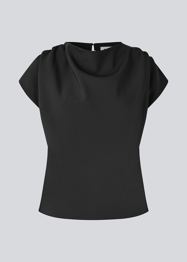 Fitted top with ruffled details. Pandymd top has short sleeves and an opening in the back with button closure.