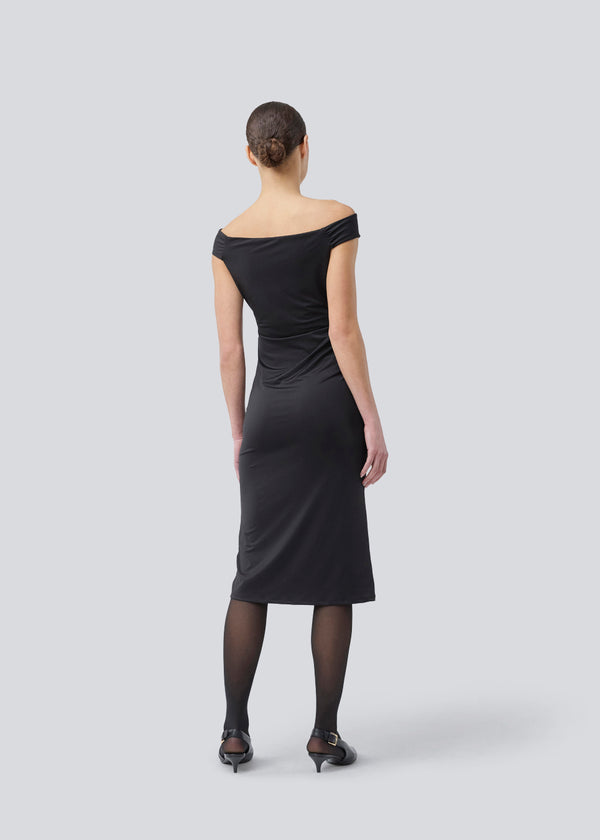 Long off-shoulder dress in elastic recycled material. Parissamd dress is fitted and has ruffle details at the sides. The model is 175 cm and wears a size S/36.
