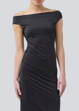 Long off-shoulder dress in elastic recycled material. Parissamd dress is fitted and has ruffle details at the sides. The model is 175 cm and wears a size S/36.