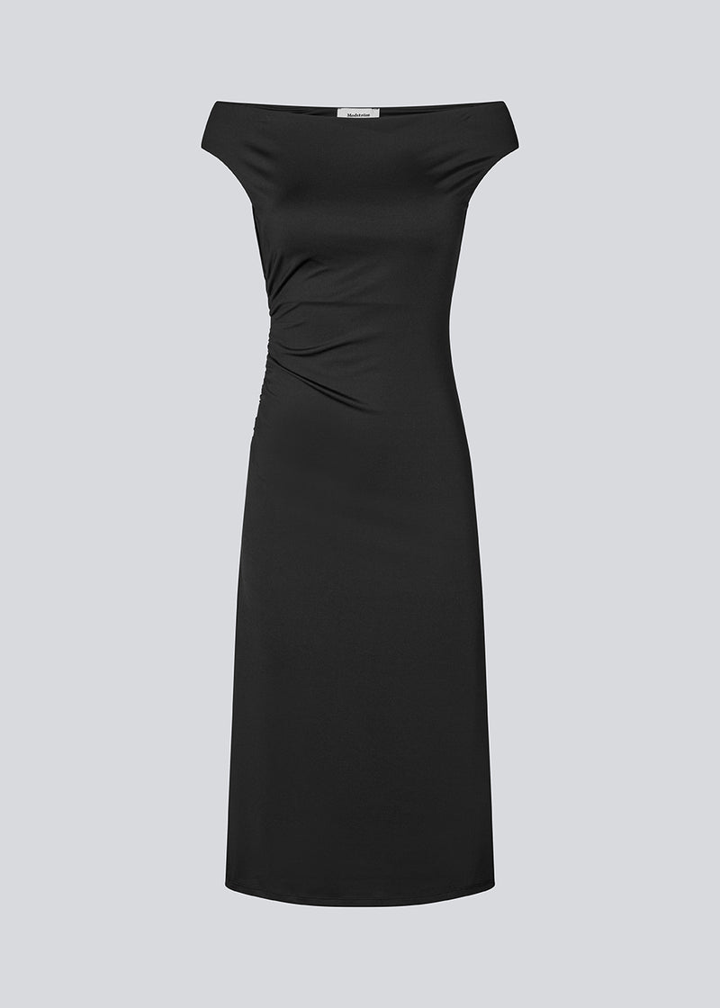 Long off-shoulder dress in elastic recycled material. Parissamd dress is fitted and has ruffle details at the sides. The model is 175 cm and wears a size S/36.